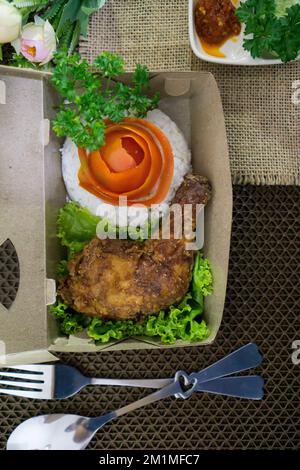 Plats indonésiens faits maison, beurre de poulet avec riz blanc, légumes, tomates et sauce Chili Banque D'Images