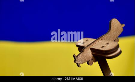Avion décoratif en bois sur fond bleu jaune du drapeau ukrainien. La Russie a attaqué l'Ukraine en 2022 Banque D'Images