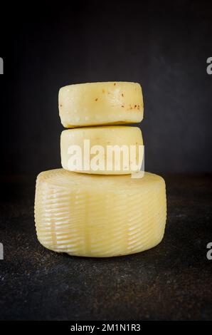 Beaucoup de différentes sortes de têtes de fromage sur table sombre. Têtes de fromage dures moyennes sur planche à découper en bois. Concept de saine alimentation biologique. Fromage fait à la main Banque D'Images