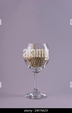 noël dans un verre de vin. La pluie du nouvel an dans un verre sur un fond Uni. Banque D'Images