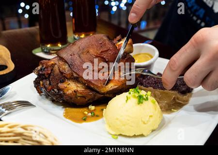 Jarret de porc cuit avec de la choucroute et purée de pommes de terre sur une table en bois. Une grande portion de porc grillé et de bière sur la table dans le pub. Banque D'Images