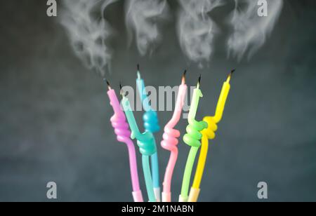 Bougies d'anniversaire avec une flamme grillée avec de la fumée qui coule sur fond sombre Banque D'Images