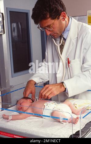 Jeune médecin de sexe masculin à l'écoute des paramètres vitaux du nouveau-né Banque D'Images
