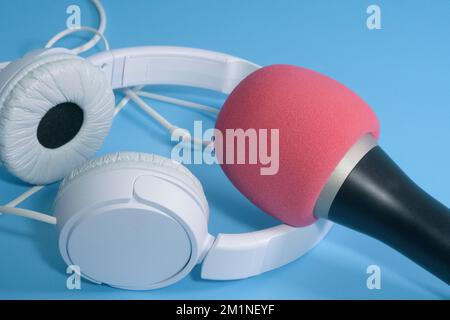 Casque et microphone blancs avec bouchon filtrant rouge pour parler et enregistrer. sur fond bleu clair. Banque D'Images