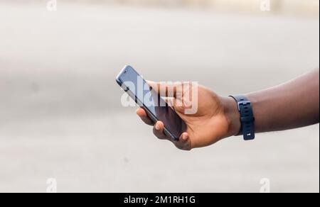 Main du jeune homme africain noir tenant un smartphone blanc à écran blanc Banque D'Images