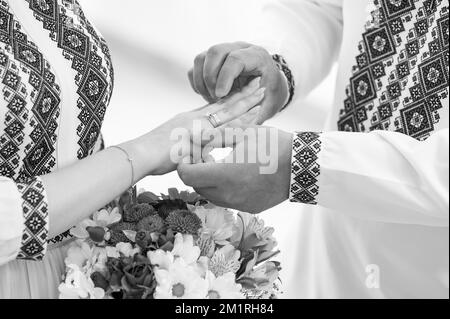 Cérémonie de mariage, jeunes couples échangeant des anneaux le jour du mariage, mains en gros plan, photo en noir et blanc. Banque D'Images