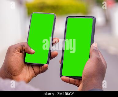 Main d'un jeune africain noir vu de côté tenant un smartphone sur un chantier de construction dans la ville Banque D'Images