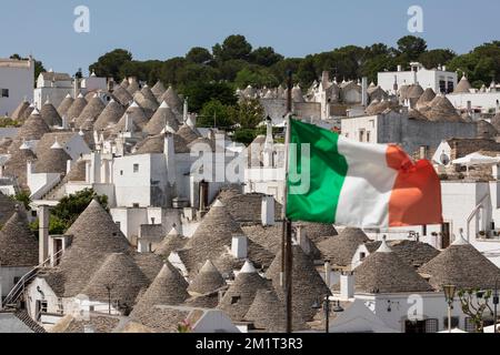 Toits coniques de maisons trulli avec drapeau italien dans la vieille ville, Alberobello, Puglia, Italie, Europe Banque D'Images