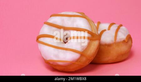 mini beignets avec glaçage au sucre et caramel sur fond rose Banque D'Images