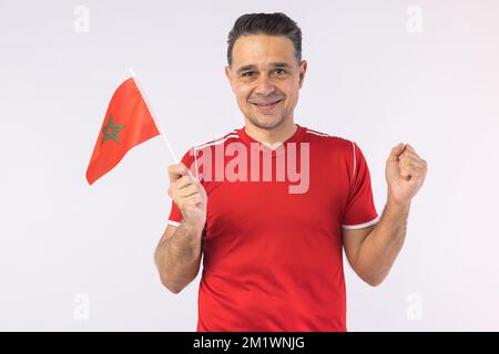 Homme portant une chemise rouge, portant un drapeau marocain. Sport, coupe du monde et concept de fan. Banque D'Images