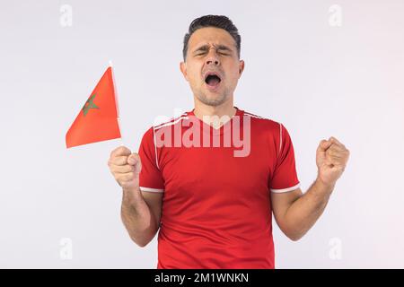 Homme portant une chemise rouge, portant un drapeau marocain. Sport, coupe du monde et concept de fan. Banque D'Images