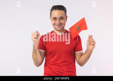 Homme portant une chemise rouge, portant un drapeau marocain. Sport, coupe du monde et concept de fan. Banque D'Images