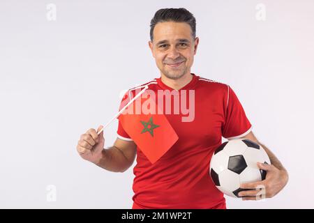 Homme portant une chemise marocaine rouge, portant un drapeau marocain. Sport, coupe du monde et concept de fan. Banque D'Images