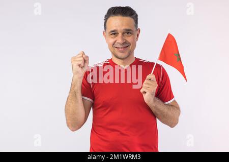 Homme portant une chemise rouge, portant un drapeau marocain. Sport, coupe du monde et concept de fan. Banque D'Images