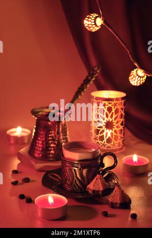 Cafetière turque et tasse traditionnelle avec bonbons orientaux. Lanterne en métal, guirlande ornée et lampes à thé. Viva magenta, couleur de l'année 2023. Rouge Banque D'Images