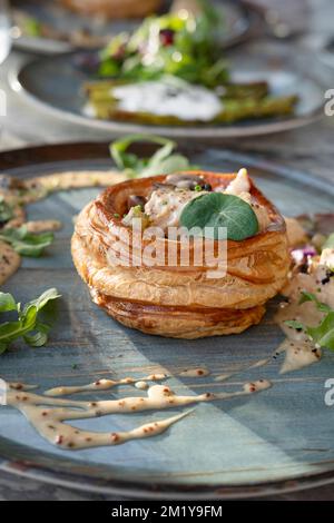 Poulet et champignons vol-au-vent sur une plaque en céramique élégante, délicieux plat chaud avec des coquilles creuses de pâte feuilletée et crémeuse Banque D'Images