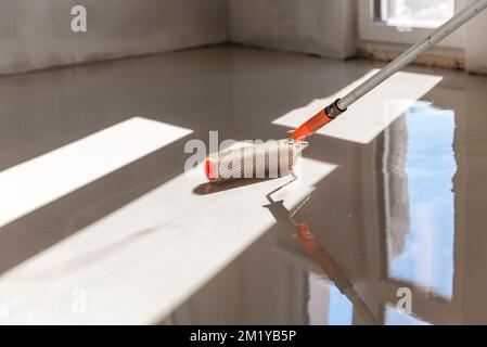 Rouleau à aiguilles pour sols auto-nivelants. Nivellement des sols avec un mélange de ciment. Banque D'Images