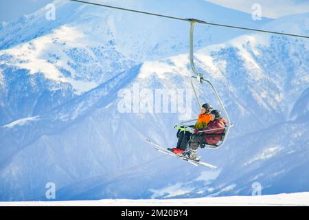 Gudauri, Géorgie - 25th mars 2022: Couple caucasien aventureux âgé en télésiège de ski pris ensemble à la retraite dans la station de ski d'hiver en vacances Banque D'Images