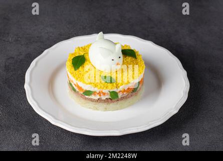 Salade feuilletée de fête Mimosa pour le nouvel an avec thon en conserve, pommes de terre et carottes, lapin décoré d'œufs Banque D'Images