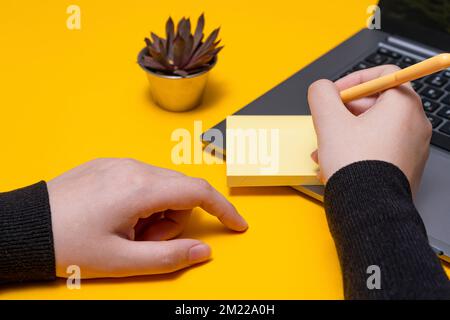 Femme tenant des notes vierges écrivant des mises à jour de Messege à côté de l'ordinateur portable. Lady Palm montrant enveloppe pliage envoi de lettres adresse postale et ordinateur de messagerie. Banque D'Images