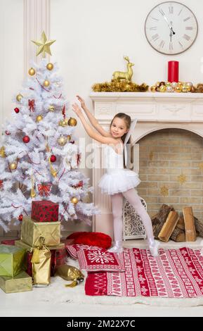 Une petite fille en costume de fée pixi décore l'arbre de Noël. Concept d'attente et de célébration de X-Mass et du nouvel an. Décoration de maison de vacances. Banque D'Images