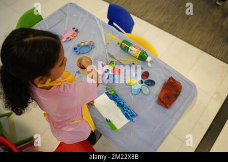Petite fille peignant avec des peintures colorées en utilisant des pinceaux et des palettes de couleurs dans sa salle de classe. Créativité et développement des enfants Banque D'Images