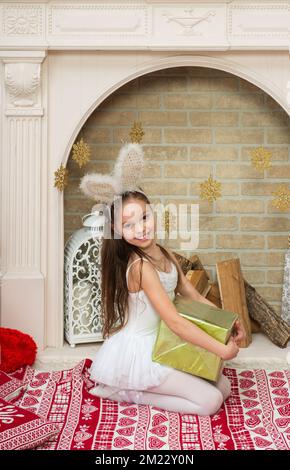 Petite fille en fée pixi costume robe avec des oreilles de rabbite tient la boîte cadeau à côté de l'arbre de Noël . X-Mass et nouvel an en attente et célébration c Banque D'Images