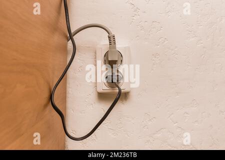 Deux fiches dans la prise dans un intérieur moderne. Concept de connexion sécurisée des appareils électriques. Banque D'Images