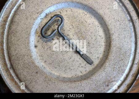 Cover of an old rusty tin can with opener on top Stock Photo