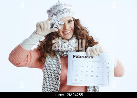 Bonjour hiver. bonne femme tendance en chandail, mitaines, chapeau et écharpe isolée sur fond blanc avec calendrier de février et flocon de neige. Banque D'Images