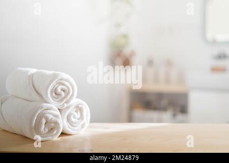 Serviettes blanches roulées sur comptoir en bois spa beauté soins du corps procédure d'hygiène dans la salle de bains. Banque D'Images
