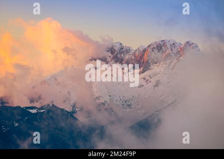 Vue sur la montagne Presolana entre les nuages sur un coucher de soleil d'hiver. Val Seriana, Castione della Presolana, Bergame district, Lombardie, Italie. Banque D'Images