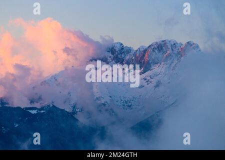 Vue sur la montagne Presolana entre les nuages sur un coucher de soleil d'hiver. Val Seriana, Castione della Presolana, Bergame district, Lombardie, Italie. Banque D'Images