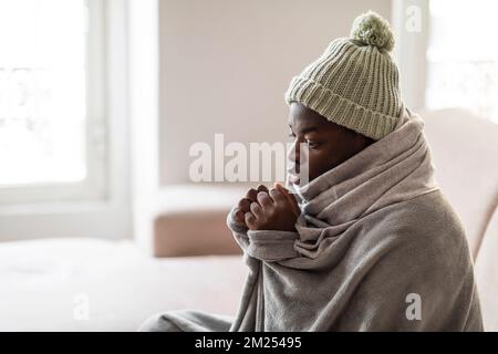 Jeune homme noir glacial assis sur un canapé dans la salle de séjour Banque D'Images