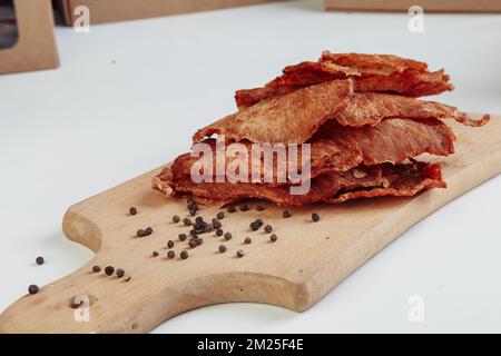 Certaines boîtes en carton de spécialité avec des friandises déshydratées pour chiens, la plus haute est ouverte, pleine de viande sèche croquante goûts de boeuf et de poulet. Animal de compagnie fait maison Banque D'Images