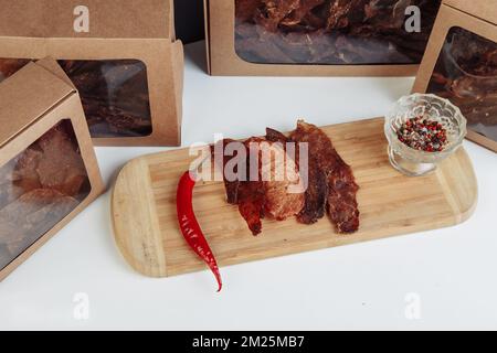 Certaines boîtes en carton de spécialité avec des friandises déshydratées pour chiens, la plus haute est ouverte, pleine de viande sèche croquante goûts de boeuf et de poulet. Animal de compagnie fait maison Banque D'Images