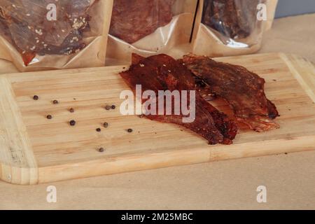 Certaines boîtes en carton de spécialité avec des friandises déshydratées pour chiens, la plus haute est ouverte, pleine de viande sèche croquante goûts de boeuf et de poulet. Animal de compagnie fait maison Banque D'Images