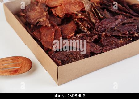 Certaines boîtes en carton de spécialité avec des friandises déshydratées pour chiens, la plus haute est ouverte, pleine de viande sèche croquante goûts de boeuf et de poulet. Animal de compagnie fait maison Banque D'Images