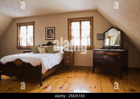 Lit double à ossature de bois dans la chambre principale à l'étage à l'intérieur de la vieille maison des années 1800. Banque D'Images