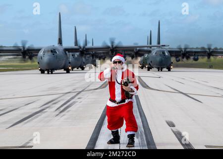 Yigo, États-Unis. 10 décembre 2022. ÉTATS-UNIS Le lieutenant-colonel Jeffrey Furnay de la Force aérienne, vêtu d'un costume de Père Noël, radio C-130 pilotes de fret qui se préparent à décoller pour l'opération Noel Drop 2022 sur la piste de la base aérienne d'Andersen, à 10 décembre 2022, à Yigo, à Guam. Sept avions C-130 des États-Unis La Force aérienne, la Royal Australian Air Force, la Japan Air Self-Defense Force, la Republic of Korea Air Force et la Royal New Zealand Air Force ont livré 71 000 livres de nourriture, de cadeaux et de fournitures pour aider les communautés insulaires éloignées du Pacifique Sud. Crédit: Yasuo Osakabe/US Airforce photo/Alamy Live N Banque D'Images