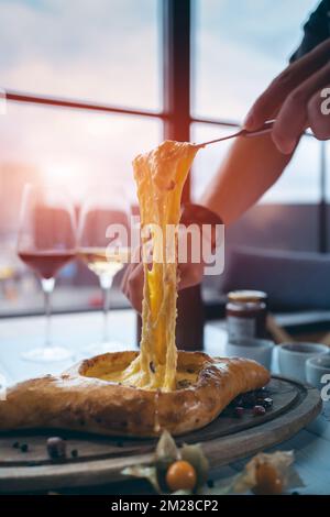 personne mélangeant du fromage suluguni et du jaune d'oeuf dans le khachapuri adjarien géorgien Banque D'Images