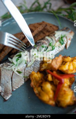 poisson de hareng frais mariné avec pommes de terre, pain brun et oignon au restaurant Banque D'Images