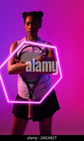 Joueuse de tennis afro-américaine attentionnée debout avec une raquette à l'hexagone illuminé Banque D'Images