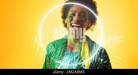 Fan afro-américain avec drapeau brésilien et peinture de visage par des plantes et un cercle illuminés Banque D'Images