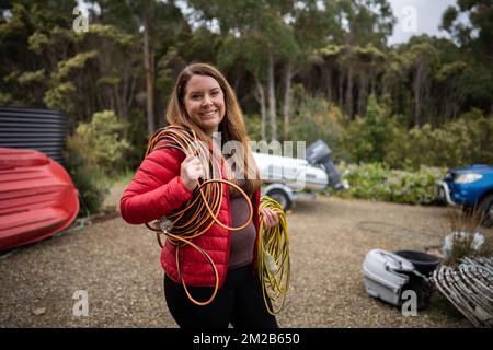 belle femme électricien transportant des rallonges sur un site de travail en australie Banque D'Images