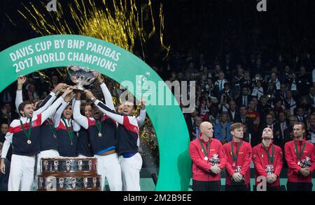 L'équipe française célèbre sa victoire alors que le capitaine belge Johan Van Herck, le belge David Goffin, le belge Steve Darcis et le belge Ruben Bemelmans se sont abattus après un match de tennis entre le belge Steve Darcis et le français Lucas Pouille, Cinquième et dernier match de la finale du Groupe mondial de la coupe Davis entre la France et la Belgique, dimanche 26 novembre 2017, à Villeneuve-d'Ascq. La France remporte la finale du Groupe mondial de la coupe Davis. BELGA PHOTO BENOIT DOPPAGNE Banque D'Images