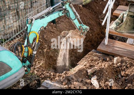 Une minipelle creuse une tranchée pour poser les tuyaux. Gros plan d'une pelle hydraulique creusant une tranchée profonde. Une pelle hydraulique creuse une tranchée dans la campagne pour déposer un Banque D'Images