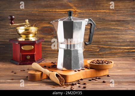 Planche avec cafetière geyser, pelle, assiette de haricots et moulin sur fond de bois Banque D'Images