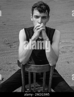 Portrait de l'homme assis sur une chaise dans le désert. Noir et blanc Banque D'Images