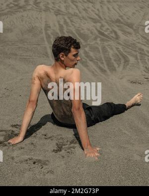 Homme solitaire assis sur le sable dans un désert sablonneux Banque D'Images